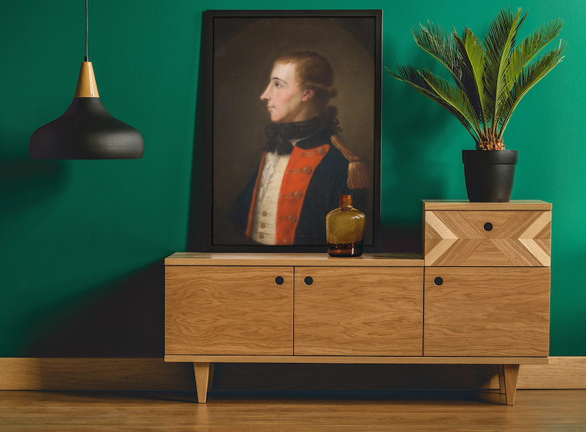 Framed reproduction print of Wolfe Tone in French military uniform, Irish revolutionary leader, Wooden cabinet with decorative items against a green wall