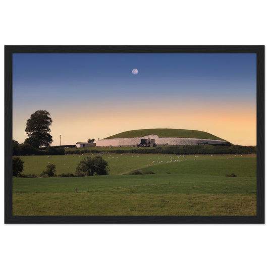 Newgrange passage tomb at sunset with the moon over green fields, framed print in a black frame