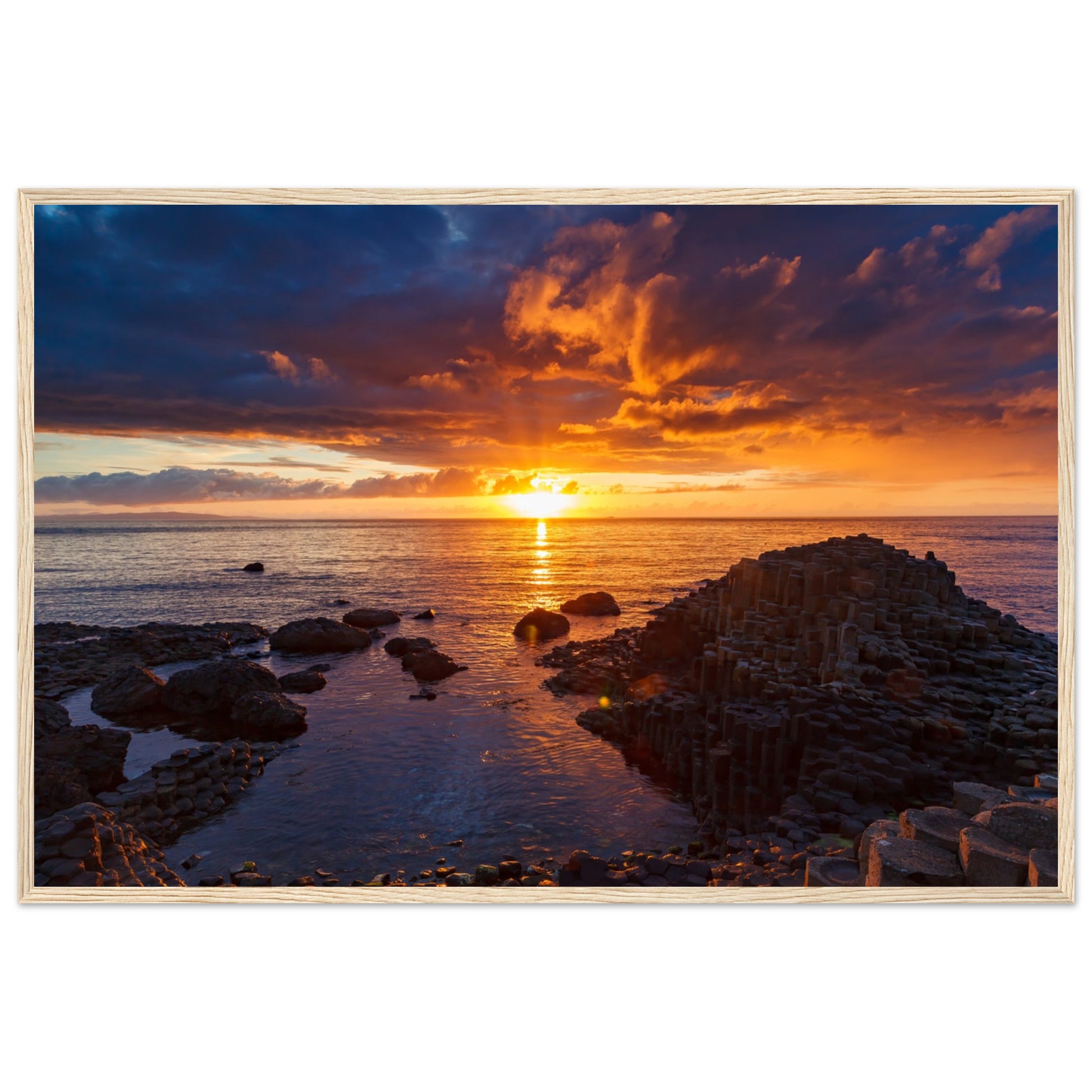 Framed art print of a mesmerizing sunset at Giant's Causeway, showcasing iconic basalt columns against a sky painted with warm hues. The scene captures nature's beauty and tranquility, adding a sophisticated touch to home or office decor. Perfect for any art lover.