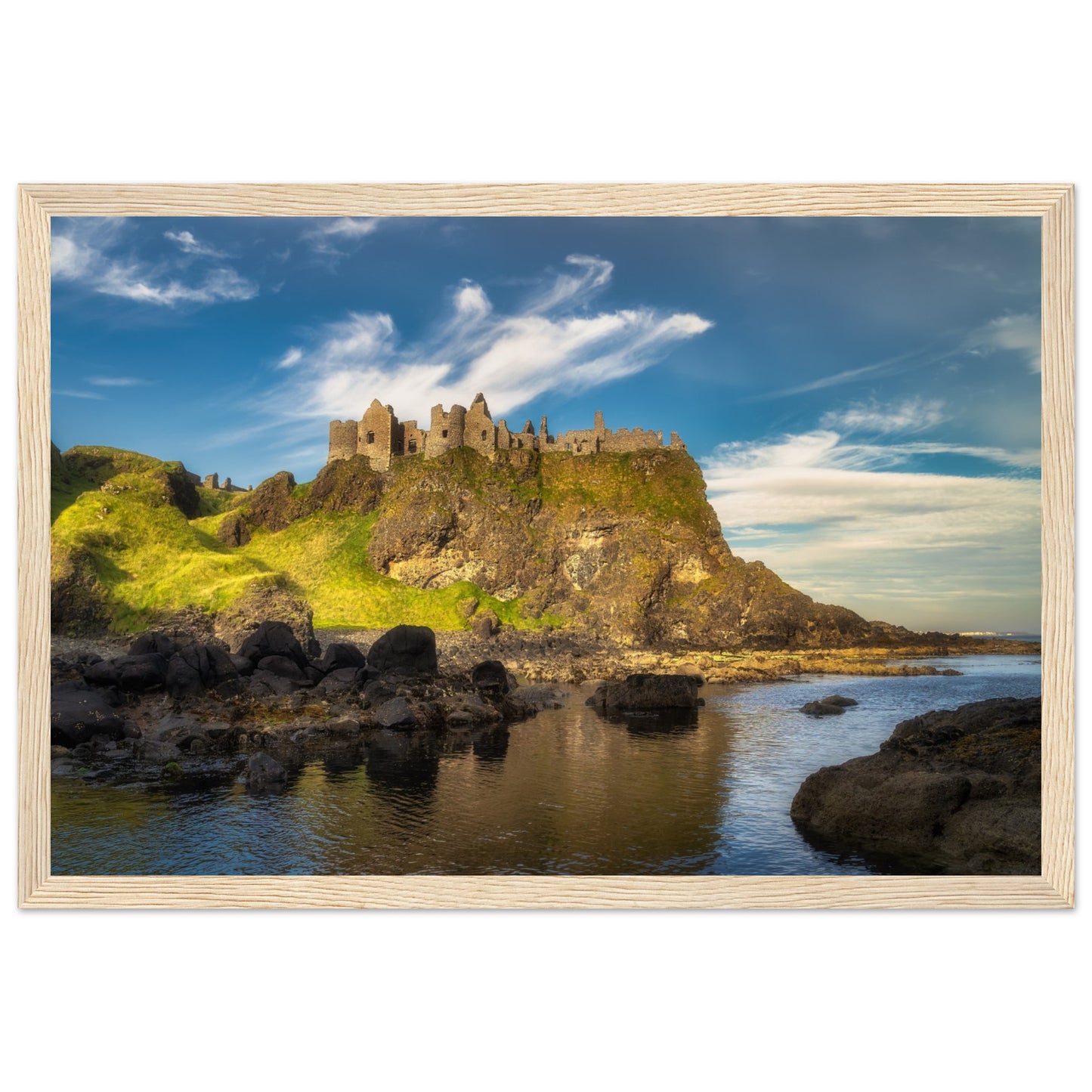 Framed wall art print of Dunluce Castle perched on rugged cliffs in Northern Ireland. The medieval ruins, set against a dramatic coastal backdrop, capture the castle's historic and scenic beauty. Perfect for adding a touch of elegance and history to any room.