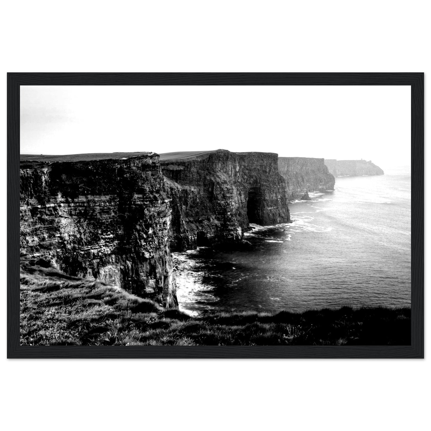 Monochrome photo of Cliffs of Moher, framed elegantly. Captures rugged beauty, contrasts. Minimalist frame complements decor. Evokes awe.