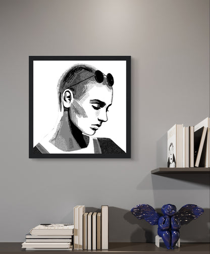 Sinéad O'Connor portrait print in a black frame above wall shelves with books on a grey wall