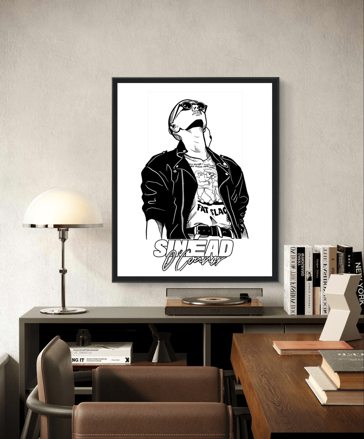 Black and white Sinéad O'Connor portrait print in a black frame above a desk with a lamp