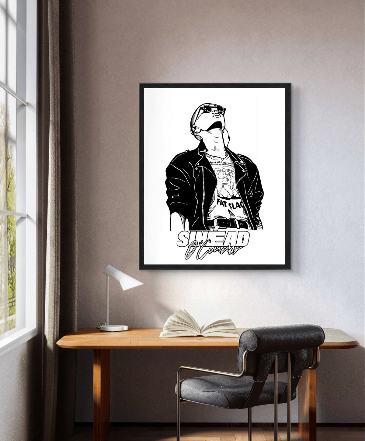 Black and white Sinéad O'Connor portrait print in a black frame above a desk by a window