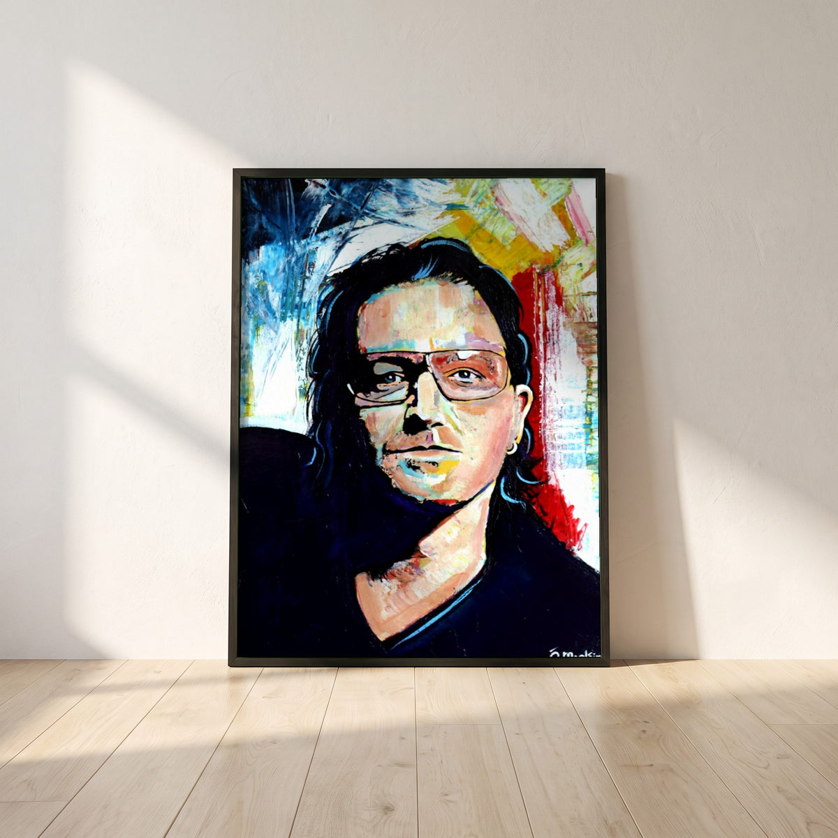 Vibrant Bono U2 framed print in a black frame leaning against a white plaster wall on oak floorboards in morning light