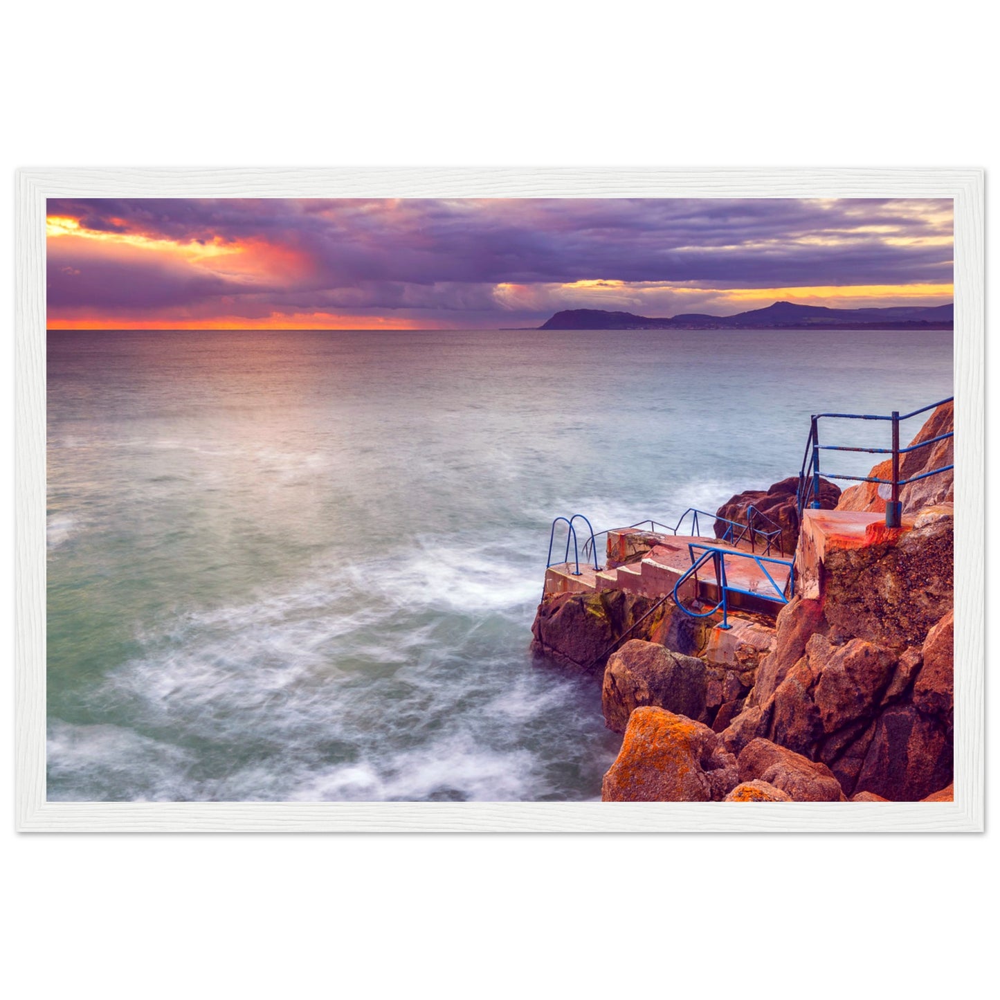 Framed wall art print of Vico Baths in Dalkey, Ireland, showcasing the scenic coastal beauty with clear waters and natural rock formations. Perfect for adding a touch of Irish charm to any room. High-quality print with vibrant colors and elegant frame.