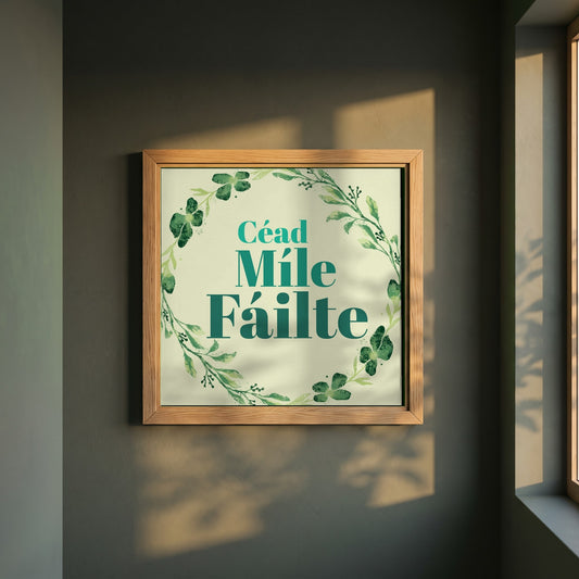 Céad Míle Fáilte framed print in a natural oak frame on a dark green wall beside a window, dappled plant shadow