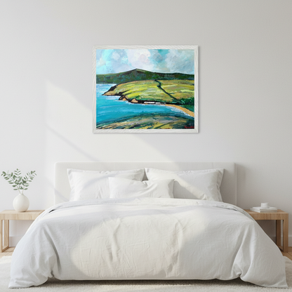 Cushendun Landscape by Ó Maoláin framed Irish art print above a bed with white linen bedding