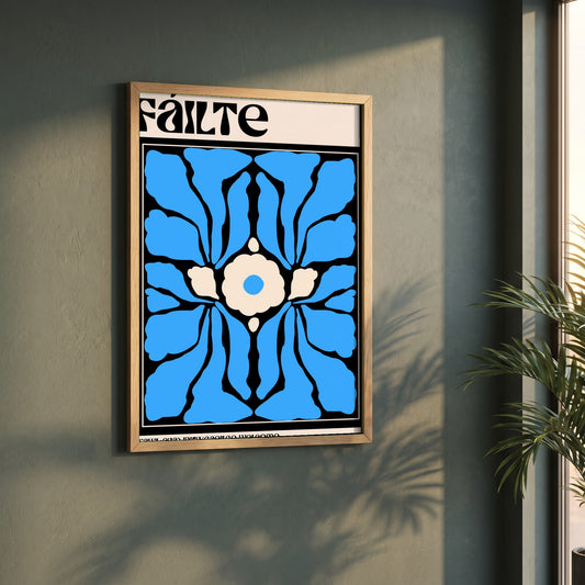 Fáilte framed print in a natural oak frame on a dark green wall beside a window, dappled plant shadow