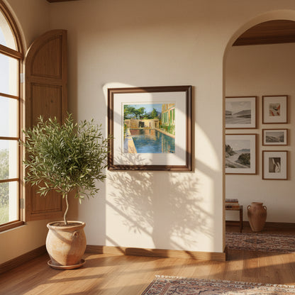 Lavery swimming pool print in a dark wood frame on a stucco wall beside an olive tree