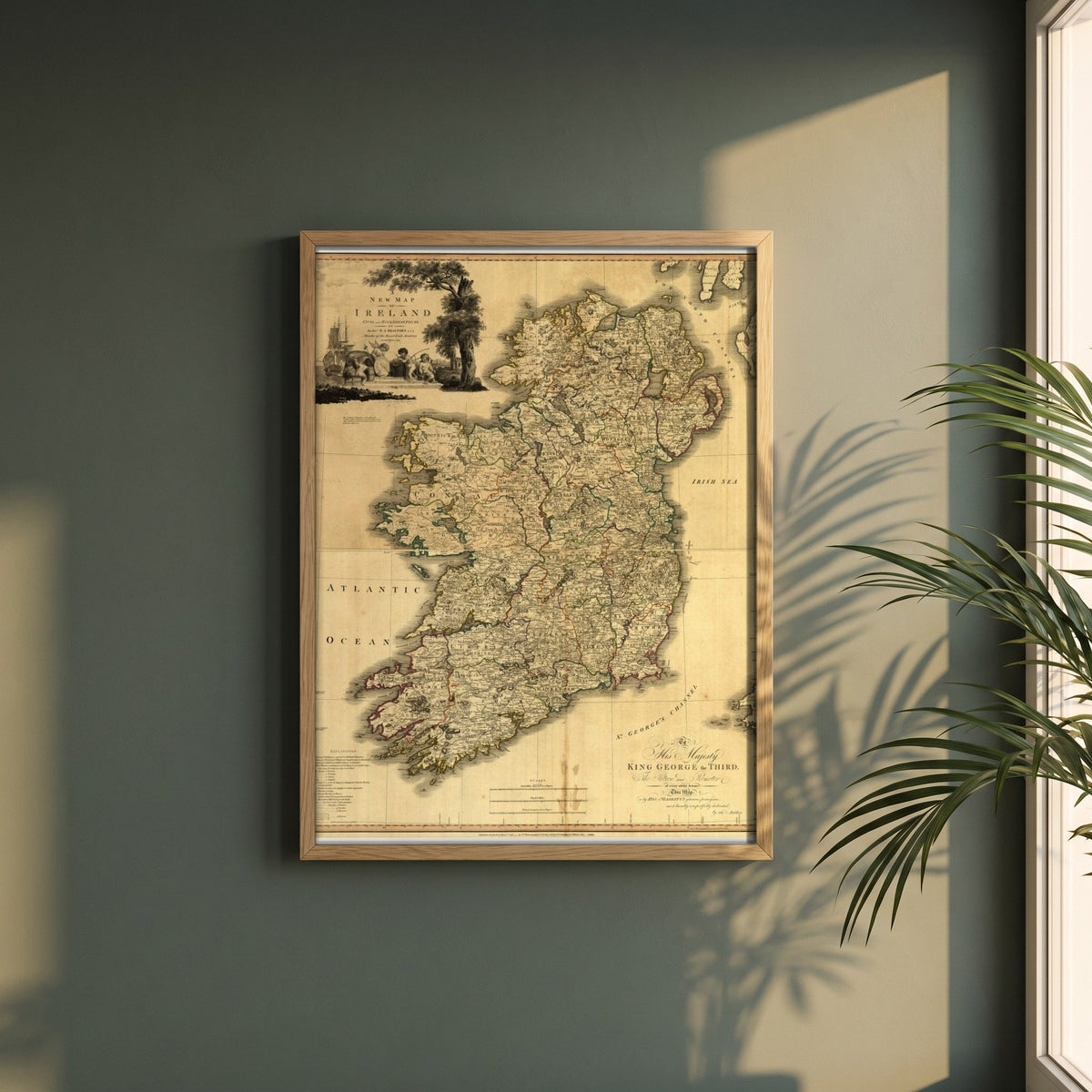 Memoir of a Map of Ireland by Daniel Augustus Beaufort framed print in a natural oak frame on a dark green wall beside a window, dappled plant shadow
