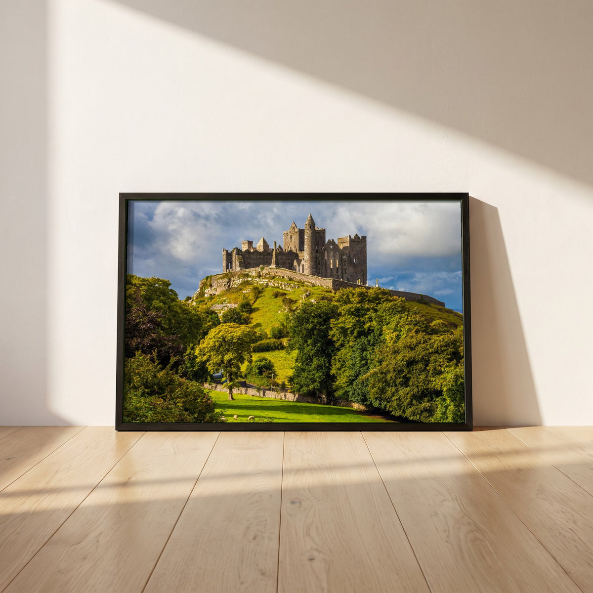 Rock of Cashel framed print in a black frame leaning against a white plaster wall on oak floorboards in morning light